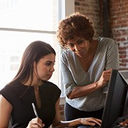 Two Businesswomen Working On Computer In Office